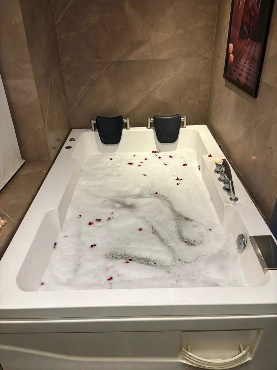 Large jacuzzi bath with rose petals and candlelight