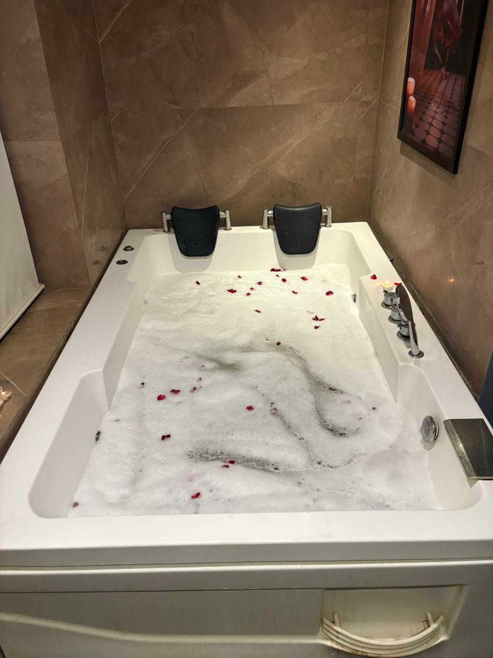 Large jacuzzi bath with rose petals and candlelight