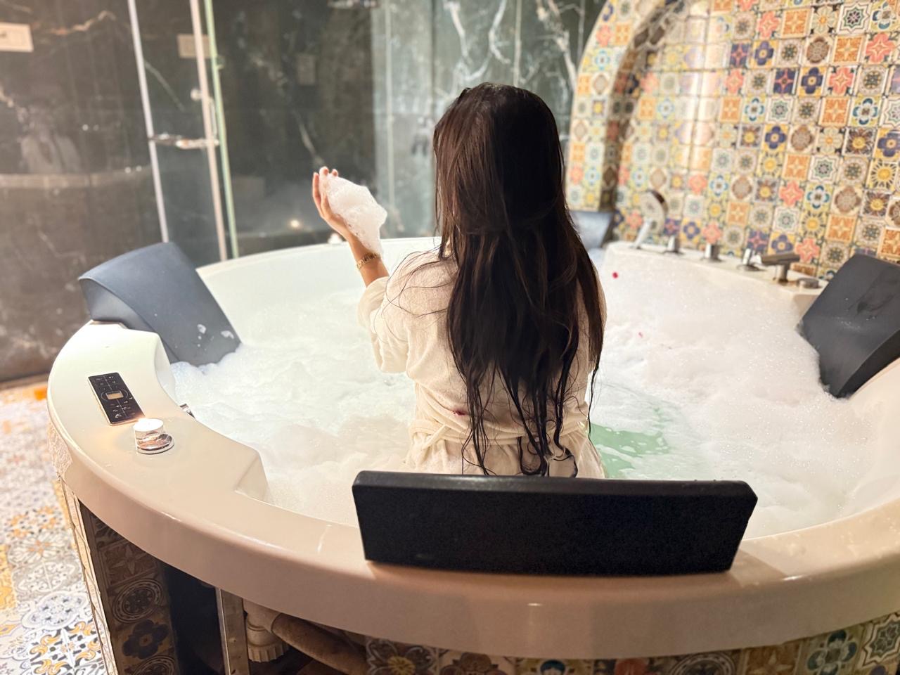Warm bubbling jacuzzi hot tub surrounded by candles at Mitram Luxury Spa